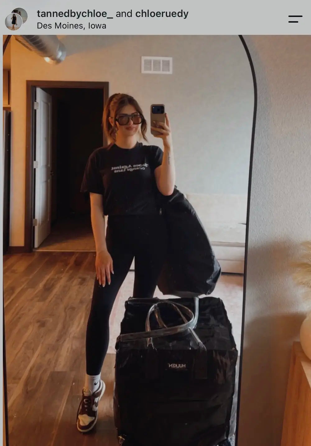 Mobile spray tan artist wearing The Glo CEO apparel beside her equipment