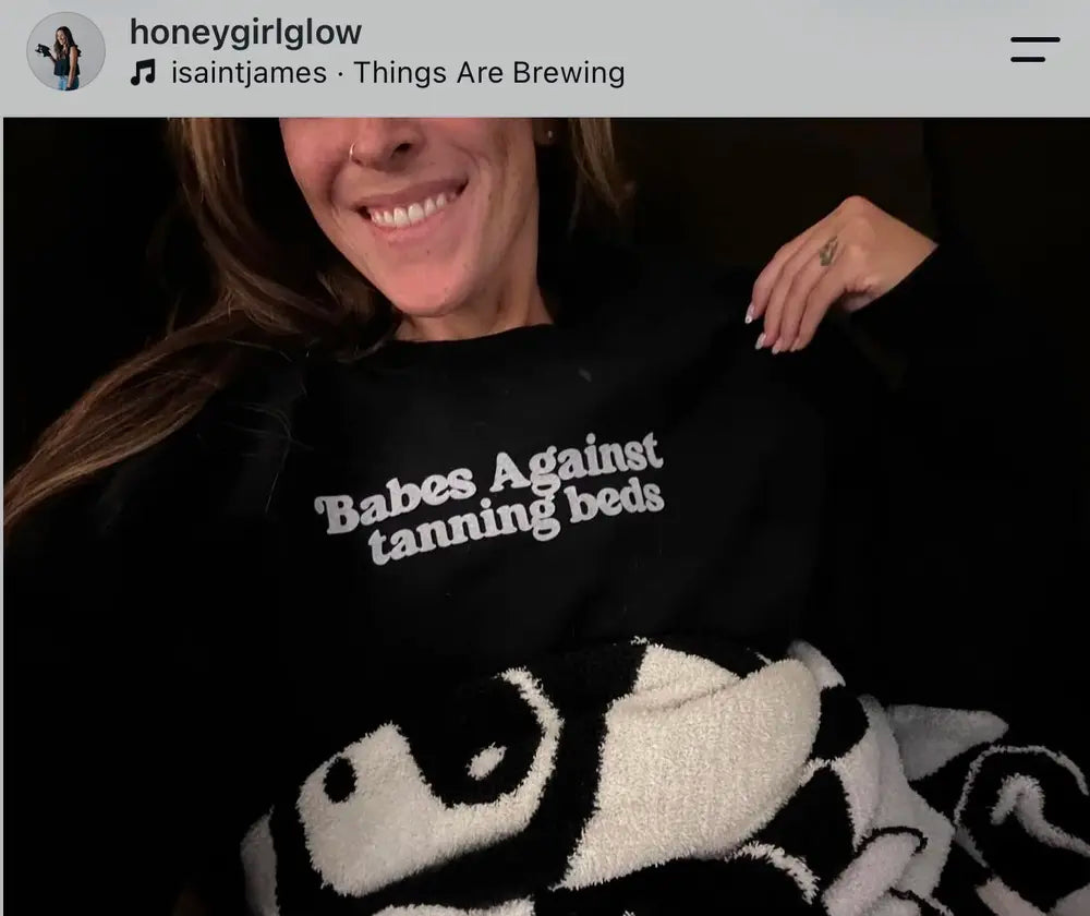 Spray tan artist wearing a Babes Against Tanning Beds shirt