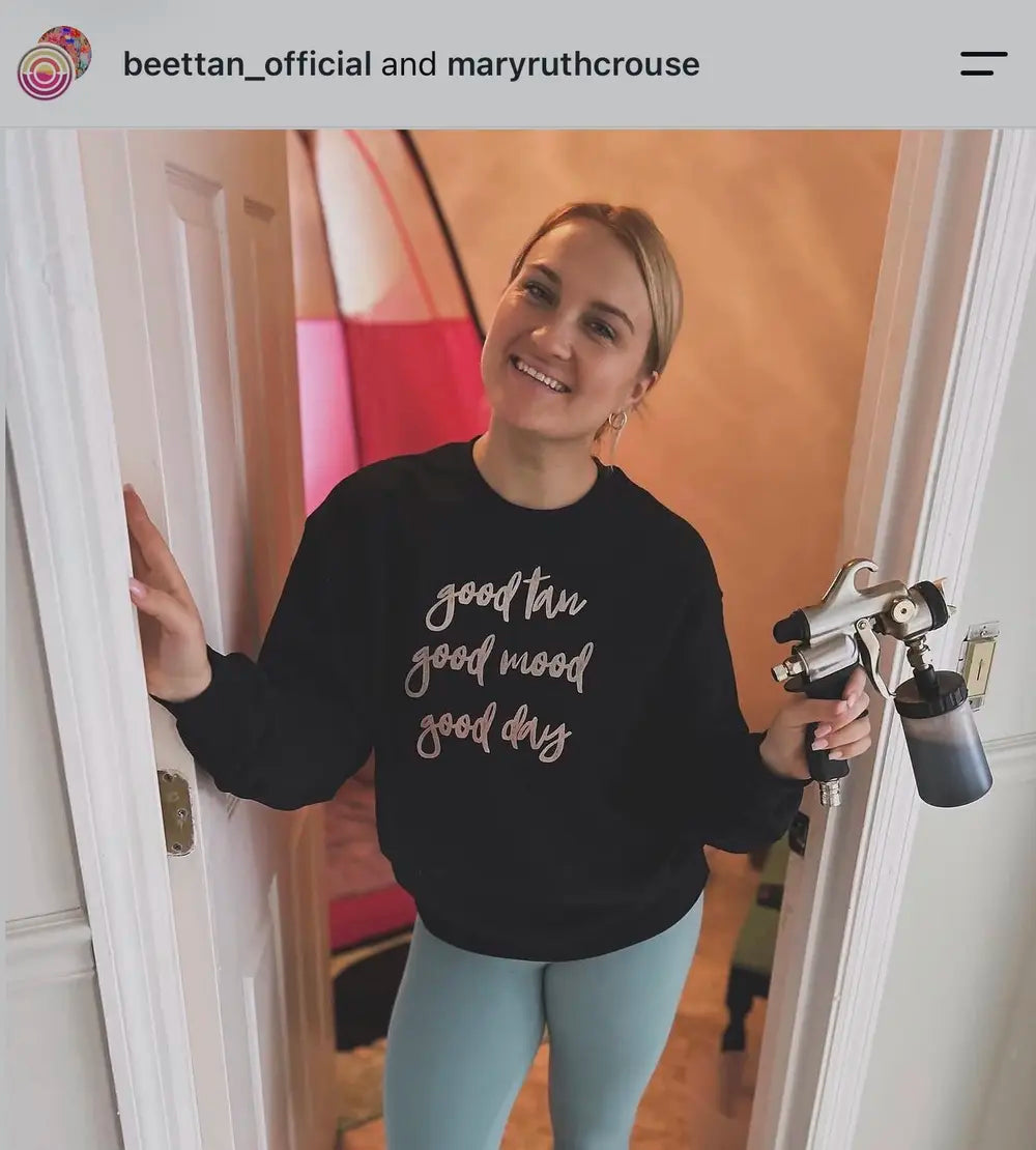 Spray tan artist wearing a Good Tan Good Mood sweatshirt